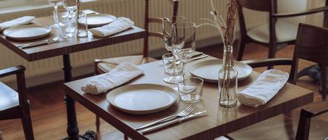 Una mesa de comedor dispuesta con platos, vasos y cubiertos, con sillas alrededor.