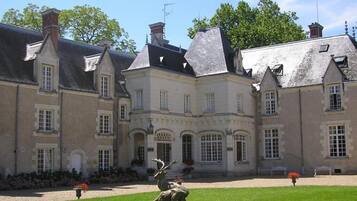 Een groot, historisch gebouw met meerdere schoorstenen en een symmetrische gevel.
