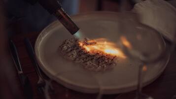 A close-up of a plate with food being toasted with a blowtorch.