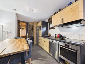 A modern kitchen with wooden cabinets, a stainless steel dishwasher, and an oven. - Prime Location Apartment - Center of Les Gets, Near Lifts, Terrace, Pet-Friendly, WiFi (Les Gets)