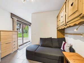 A modern room with a sofa, wooden cabinets, and a sliding glass door leading to an outdoor area. - Prime Location Apartment - Center of Les Gets, Near Lifts, Terrace, Pet-Friendly, WiFi (Les Gets)
