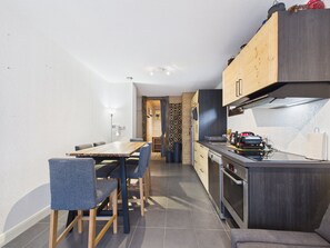 A compact kitchen with a dining area, wooden cabinets, and a built-in oven. - Prime Location Apartment - Center of Les Gets, Near Lifts, Terrace, Pet-Friendly, WiFi (Les Gets)