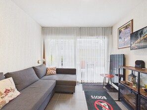 A modern living room with a grey sofa, a small round table, and a bookshelf. - Prime Location Apartment - Center of Les Gets, Near Lifts, Terrace, Pet-Friendly, WiFi (Les Gets)