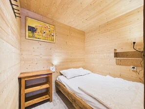 A wooden cabin room with a bed, a shelf, a painting, and a wall-mounted basket. - Prime Location Apartment - Center of Les Gets, Near Lifts, Terrace, Pet-Friendly, WiFi (Les Gets)