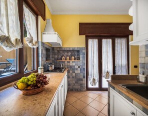 Una cocina con salpicadero de azulejos, un frutero en la encimera y vistas a través de la puerta.
