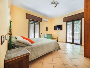 Quarto com cama, televisão e um armário verde.