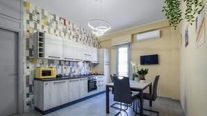 A modern kitchen with a dining area, a TV, and a plant.