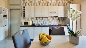 A modern kitchen with white cabinets, a microwave, and a fruit bowl on the counter.