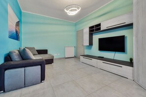 Uma sala de estar moderna com sofá, TV e unidade de entretenimento planejada.