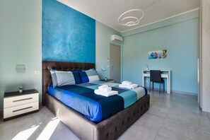 Un dormitorio con una cama grande, un escritorio y una silla.