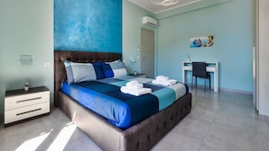 A bedroom with a large bed, a desk, and a chair.