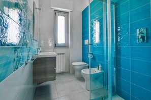 Une salle de bain avec une douche à parois de verre, des toilettes et un bidet.