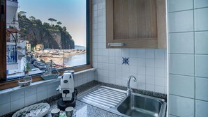A kitchen with a view of a coastal town, a sink, and a coffee maker. - Casa Mariarosa - Seaview House in Sorrento Coast (Piano di Sorrento)