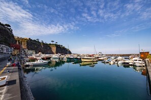 Un puerto deportivo con barcos amarrados, un acantilado rocoso y edificios a lo largo de la costa.