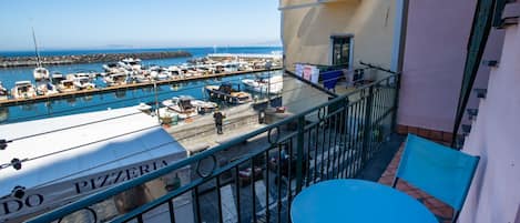 A balcony with a view of a marina, a table, and chairs.