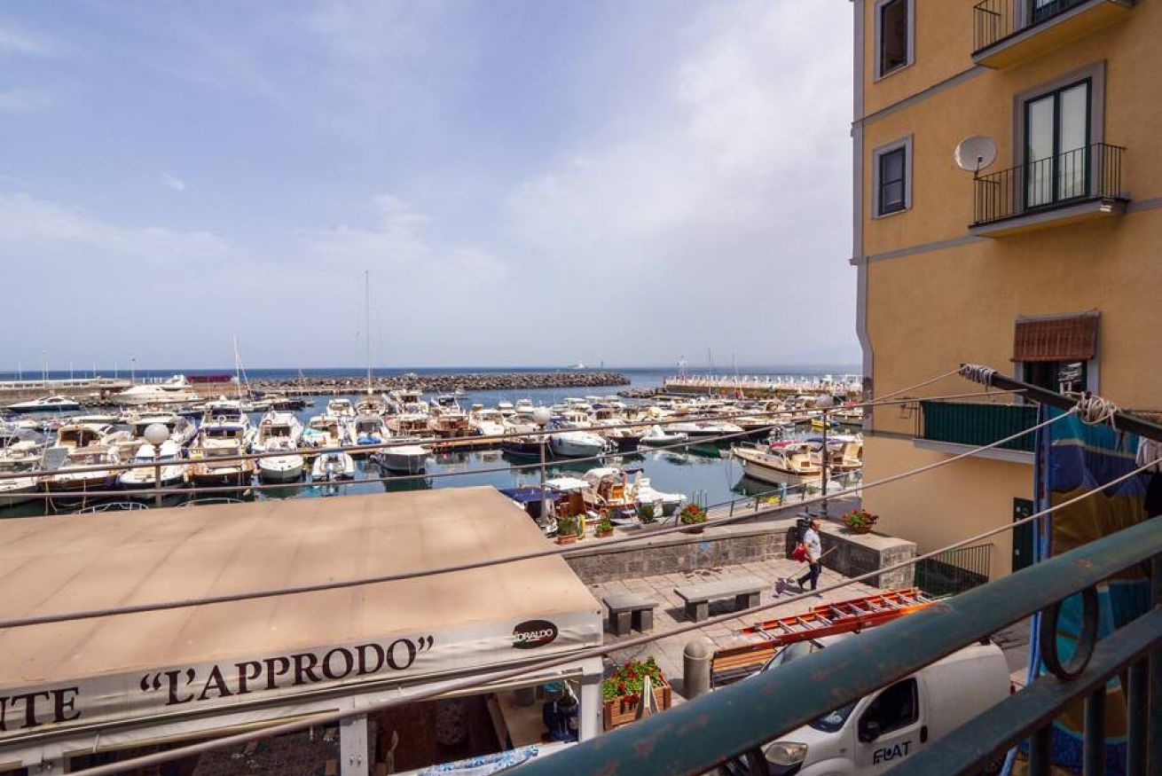 Un puerto deportivo con numerosas embarcaciones amarradas, un edificio con balcones y un letrero que dice 'L'APPRODO'.