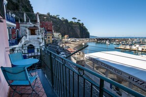 Un balcón con vistas a un puerto deportivo, un restaurante llamado 'Ristorante Capprodo PIZZA' y edificios a lo largo de la costa.