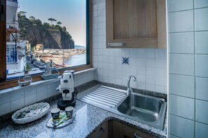 Una cocina con vistas a un pueblo costero, una cafetera y un fregadero.