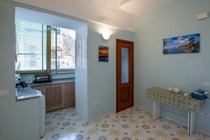 A compact kitchen with a window, a door, and a small table with a patterned tablecloth.