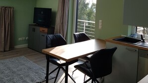 A modern kitchen with a dining area, a TV, and a window with curtains.