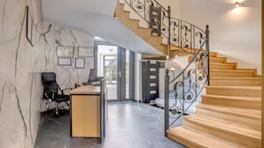 Ein modernes Interieur mit einem Holztisch, einem schwarzen Bürostuhl und einer Treppe mit Metallgeländern.