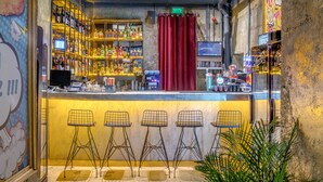 Eine Bar mit einer Theke, Regalen voller Flaschen und vier Barhocker.