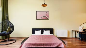A bedroom with a bed, a hanging chair, a radiator, and a framed picture on the wall.