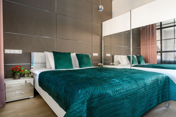 Um quarto moderno com uma cama grande, uma mesa de cabeceira com gavetas, um espelho e uma janela com cortinas.