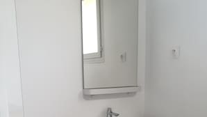 Une salle de bain avec un lavabo blanc, un meuble en bois et un miroir.