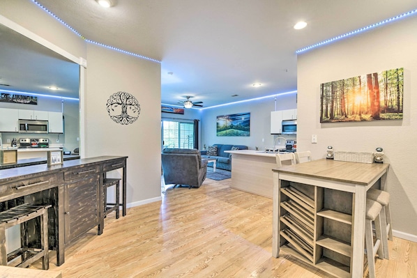Una cocina moderna con microondas, armarios y una zona de comedor con una mesa y sillas de madera.