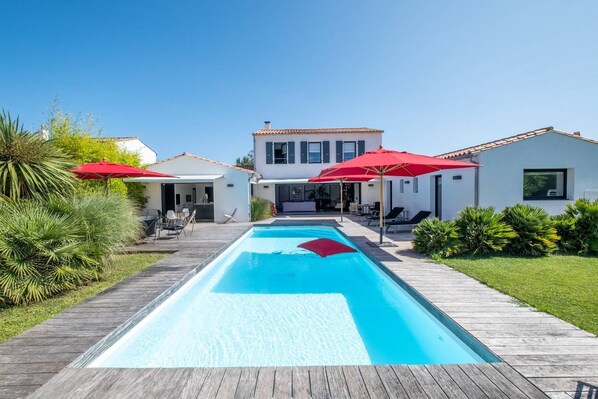 Relax by the rectangular pool surrounded by a deck and lush greenery.