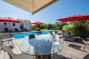 Relax by the pool surrounded by lush greenery and lounge chairs.