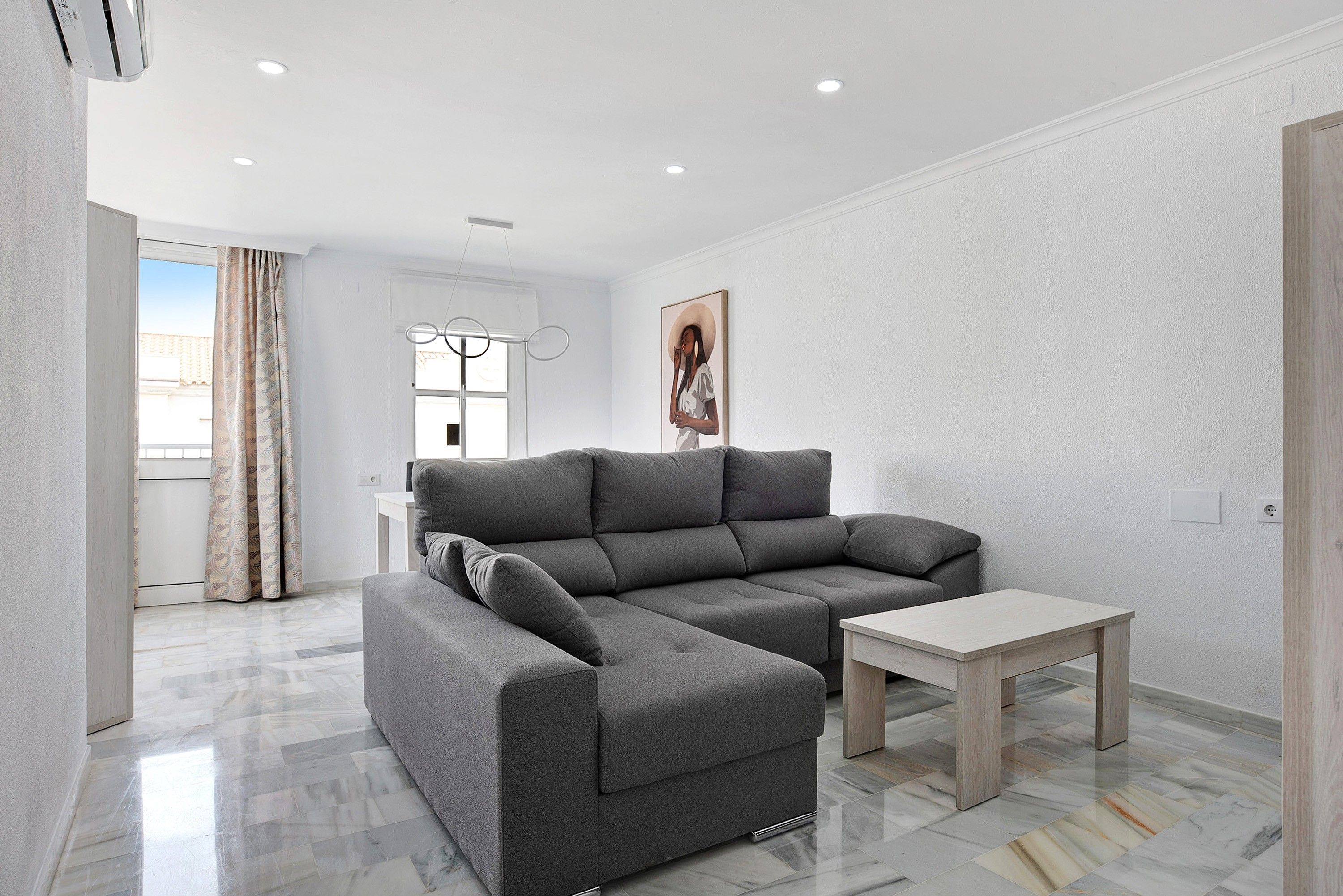 Una sala de estar moderna con un sofá seccional gris, una mesita de centro de madera y un cuadro en la pared.