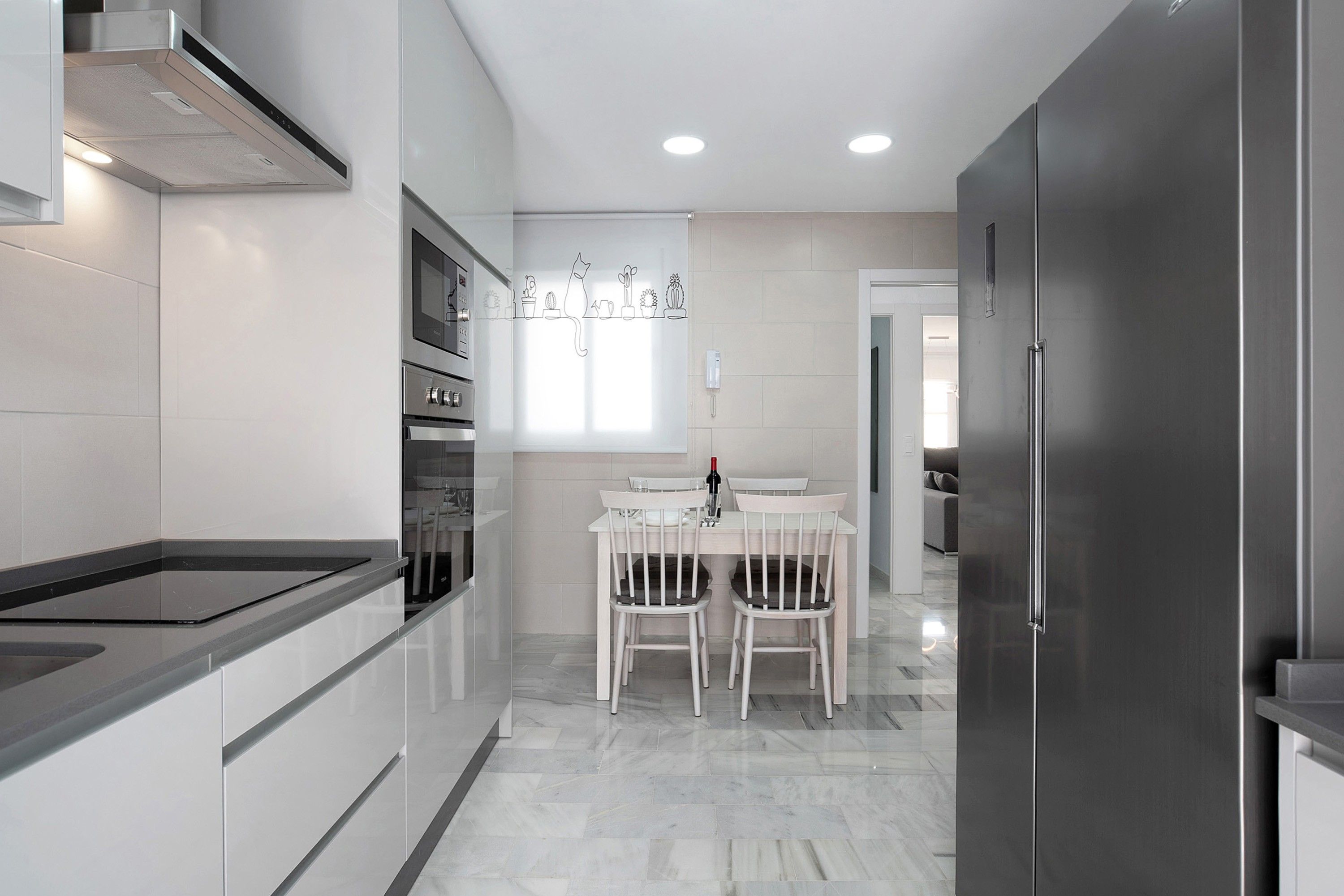 Una cocina moderna con comedor, que incluye un horno empotrado, un refrigerador y un teléfono en la pared.