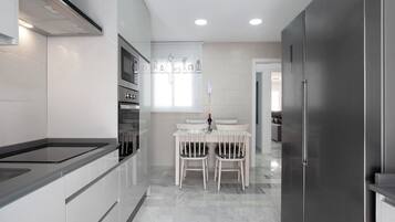 Una cocina moderna con comedor, que incluye un horno empotrado, un refrigerador y un teléfono en la pared.