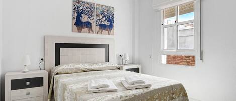 A bedroom with a bed, nightstands, a window, and artwork on the wall.