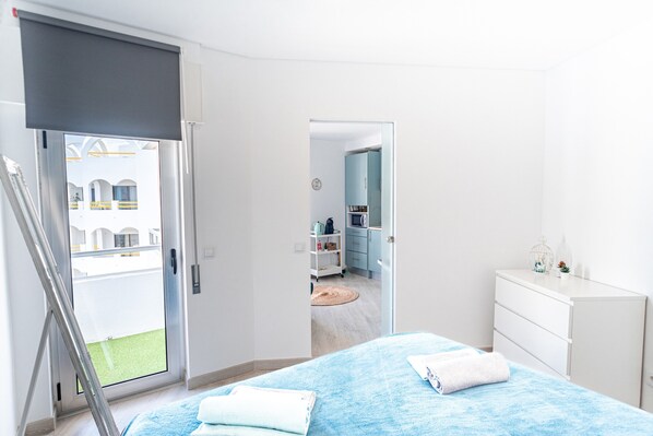 A bedroom with a large bed, a sliding door to a balcony, and a view of a building with arches.