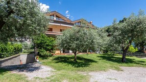 Un bâtiment doté d’un balcon, entouré d’arbres et bordé d’une zone recouverte de gravier.