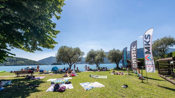 Une zone herbeuse avec des tentes, un lac et des drapeaux.