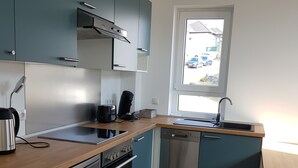 Une cuisine compacte avec des meubles de couleur turquoise, des appareils en acier inoxydable et un plan de travail en bois.