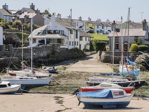 A harbor with boats docked, a narrow pathway leading to houses, and a stone wall on one side. - Old Tollgate (Holyhead)
