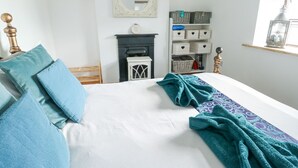 Une chambre à coucher avec un lit, une cheminée, un miroir et une étagère avec des paniers.