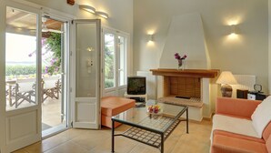 Un salon avec une table basse en verre, un canapé, un téléviseur et une cheminée.
