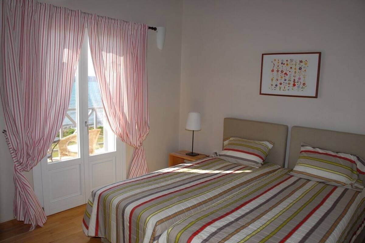 A bedroom with a bed, a nightstand, a lamp, and a window with curtains.
