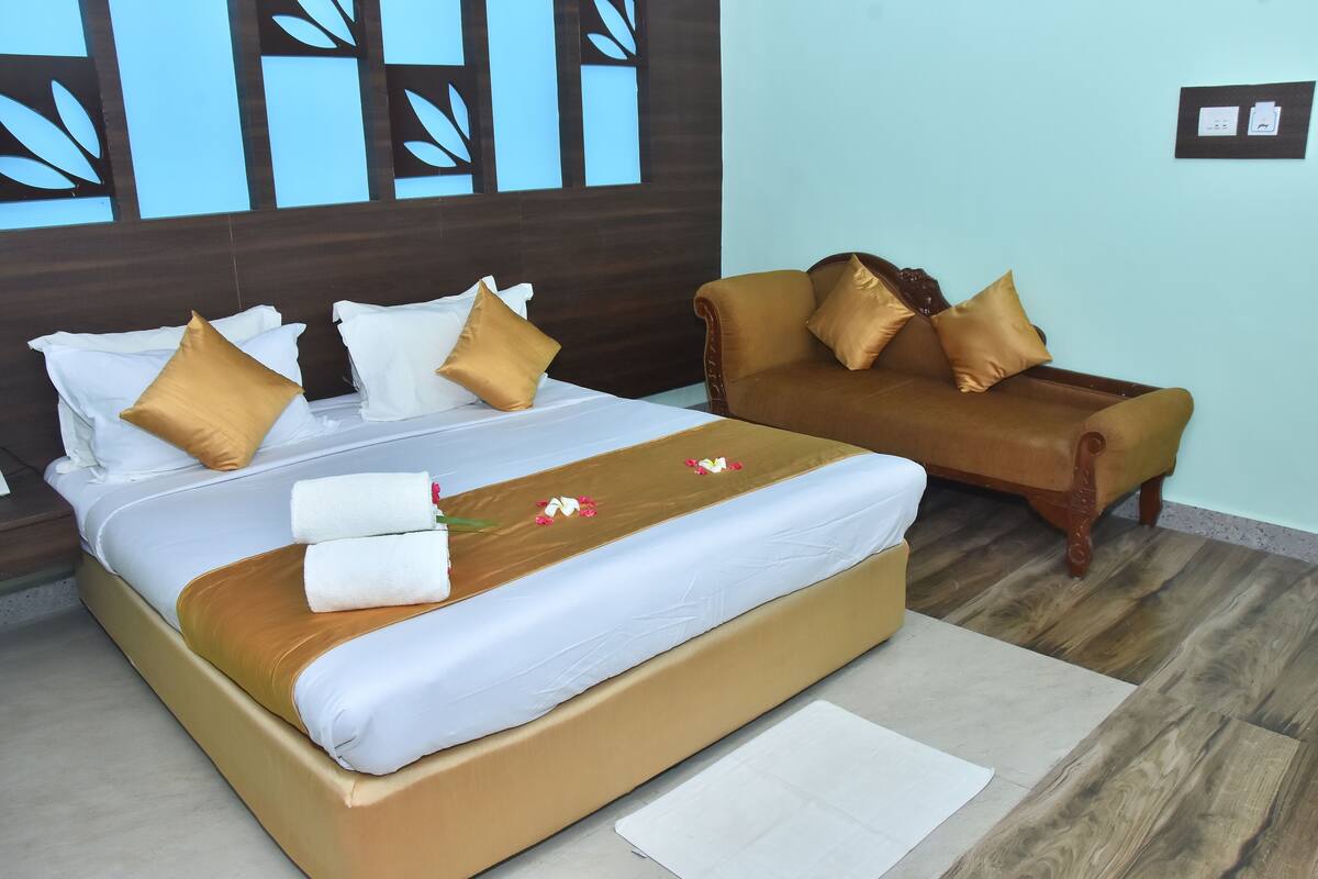 A hotel room with a bed, a sofa, and a wooden floor.