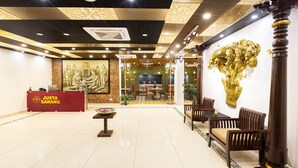 Un área de recepción con mostrador, zona de estar y una pared con una escultura de árbol dorado.