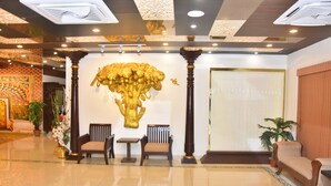Un vestíbulo con piso pulido, una escultura de árbol dorado y mobiliario de madera tradicional.