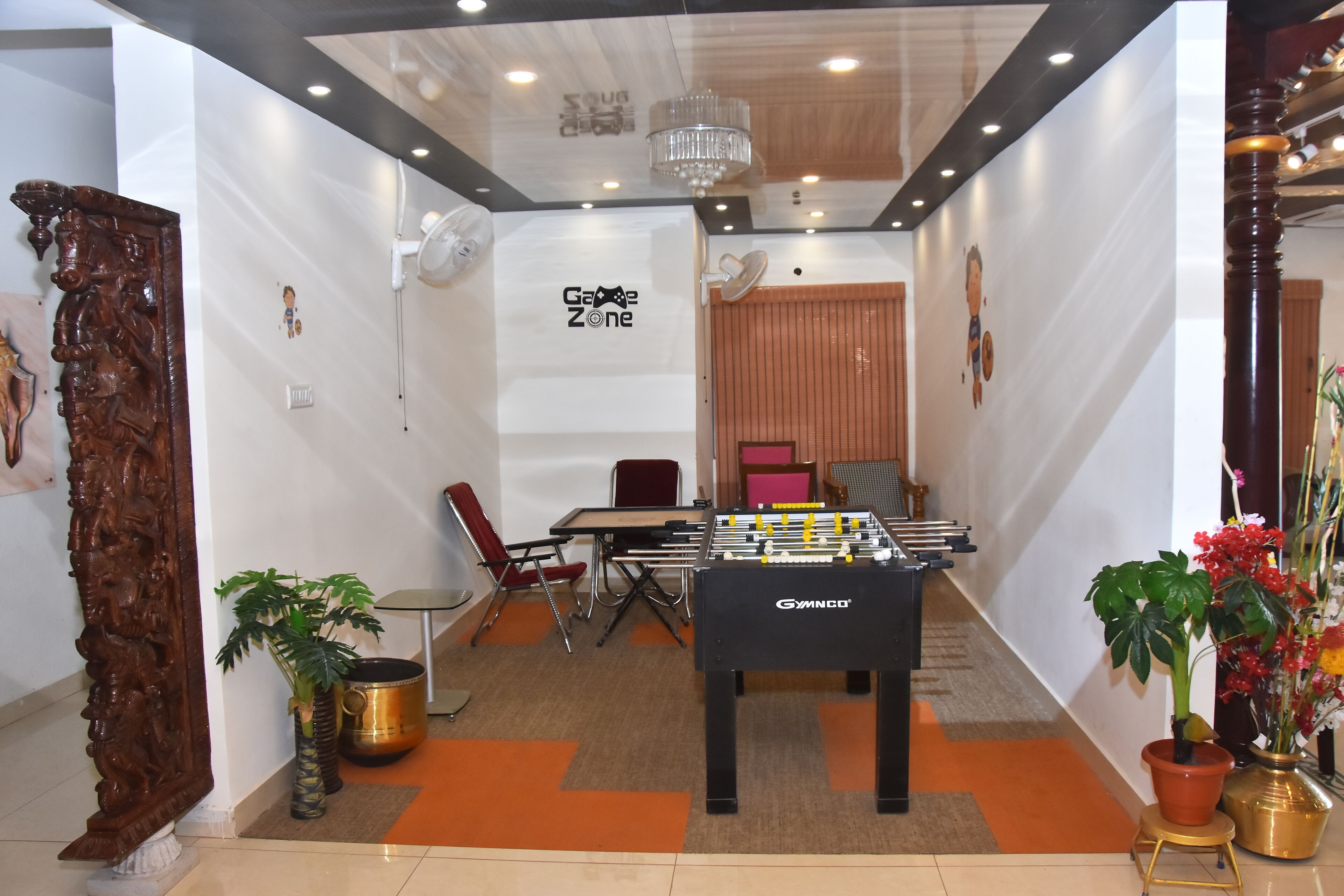 A room with a foosball table, a chandelier, and a dining area with chairs and a table.