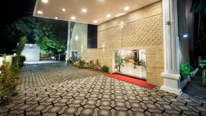Entrada de un hotel con suelo de baldosas estampadas, alfombra roja y un diseño moderno que incluye una pared y columnas de madera.