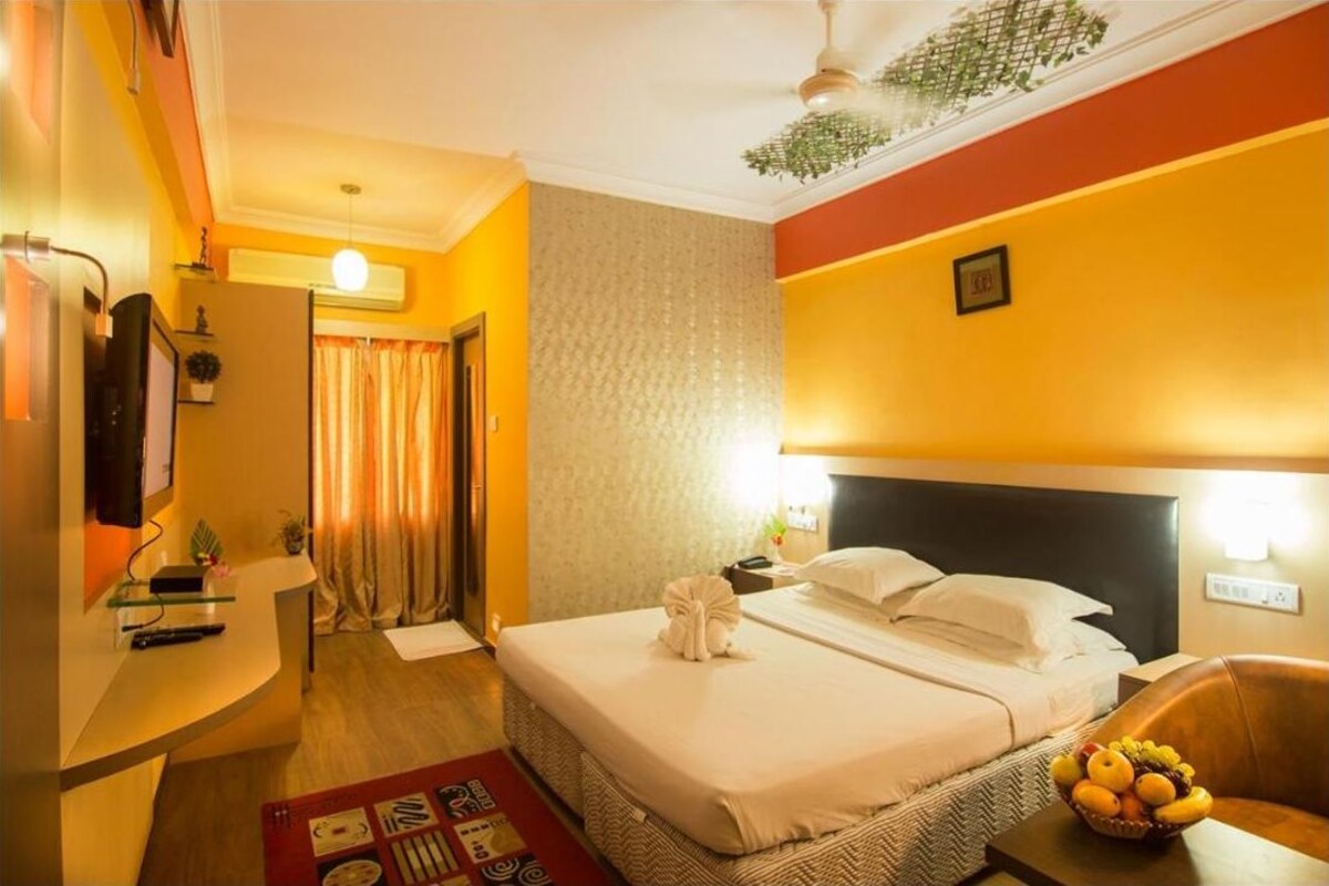 Una habitación de hotel con cama, mesita de noche y frutero.